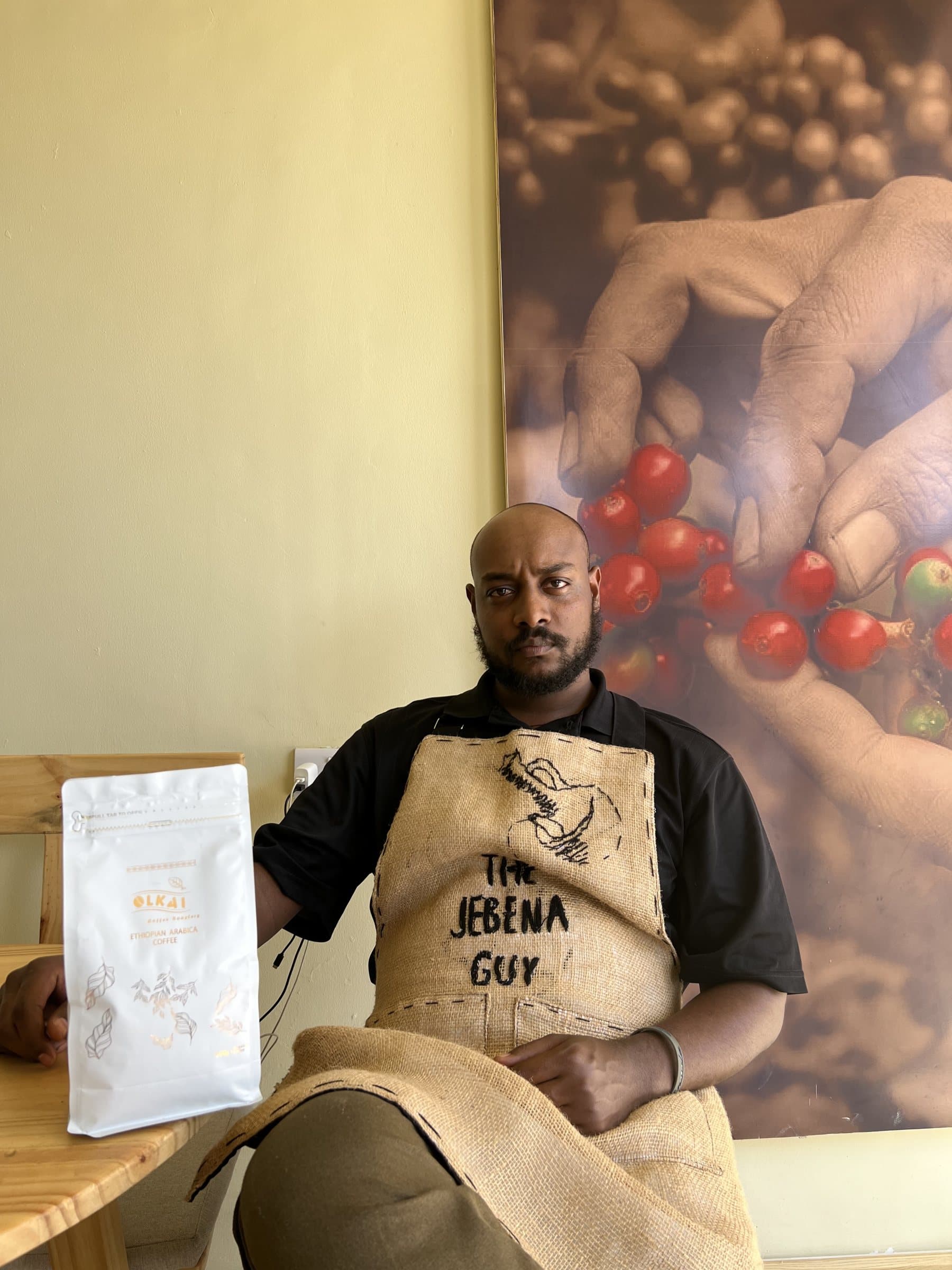 Tajur in a Jebena Guy apron beside a bag of coffee